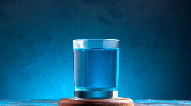 side-view-still-water-glass-wooden-cutting-board-blue-background (1)