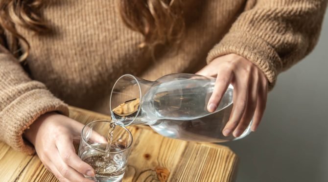 woman-pours-water-into-glass-from-glass-decanter (1)